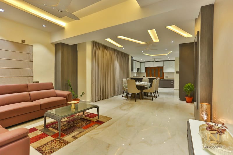 Open living-dining space with leather sofa, round dining set and layered cove-lit tray ceiling, Hyderabad home