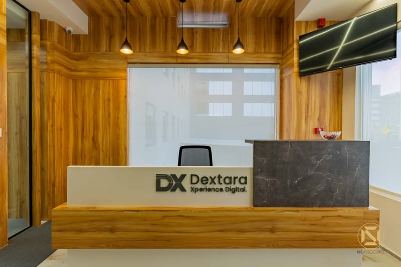 Dextara office reception with teak wood panelling, stone-clad desk, pendant lights and wall-mounted display, Hyderabad