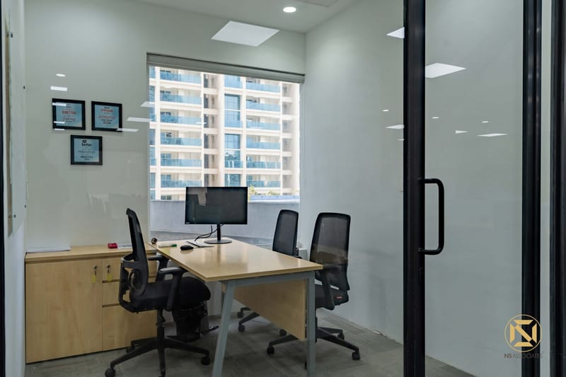 Private office cabin with light-wood desk, black mesh chairs, framed certificates and a city-view window, Hyderabad