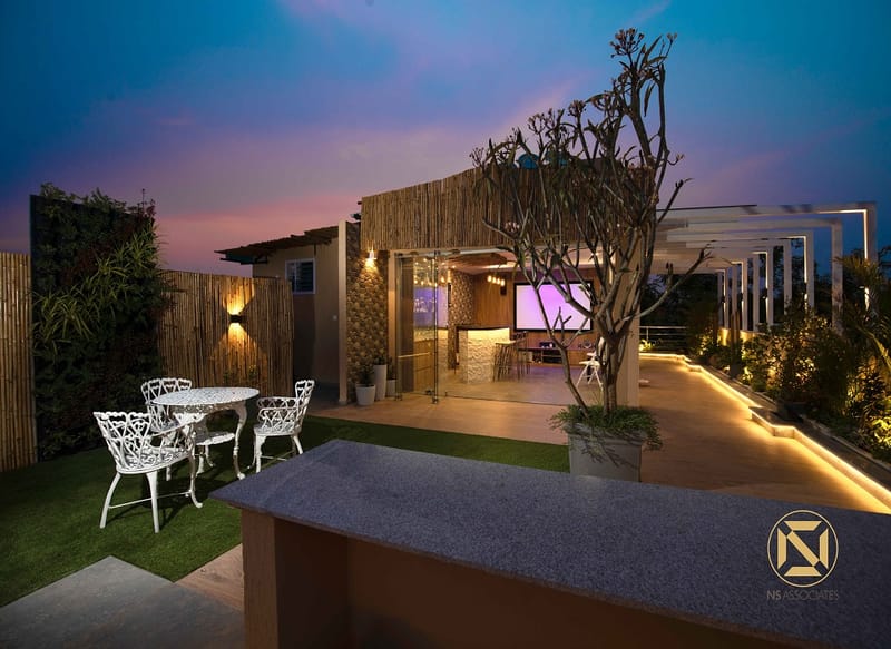 Twilight rooftop lounge with bamboo screens, vertical garden and warm strip lighting under a purple sky, Hyderabad full-home project