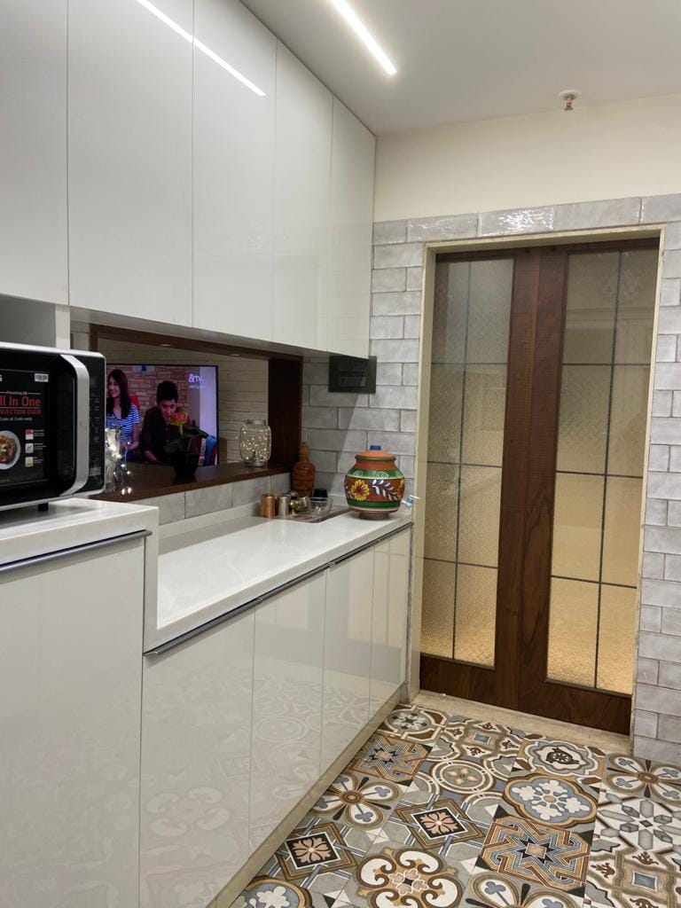 Modern kitchen with glossy white cabinets, subway tiles, patchwork Moroccan floor and glazed sliding door, Hyderabad