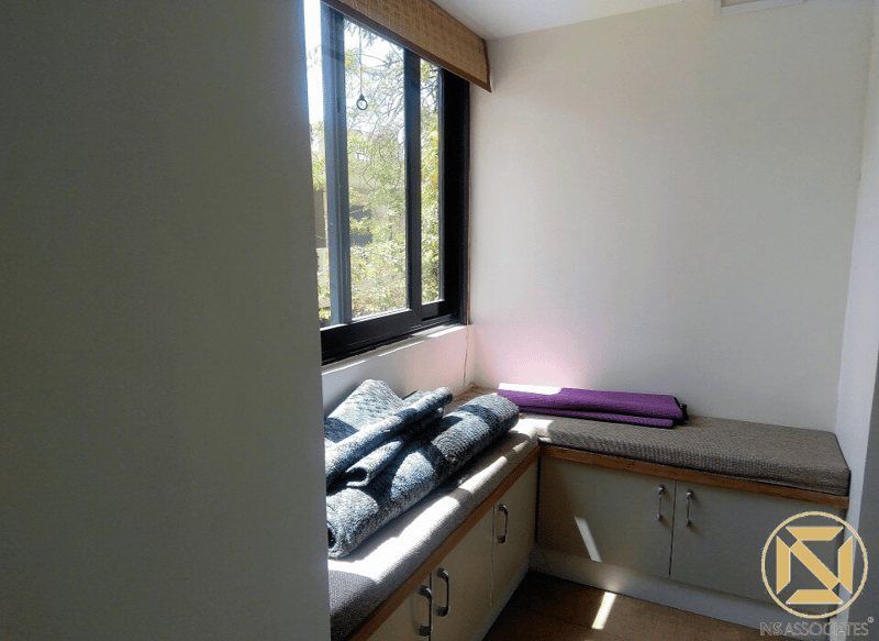 Cushioned window-seat nook with storage cabinets, folded mats and garden view, Hyderabad studio