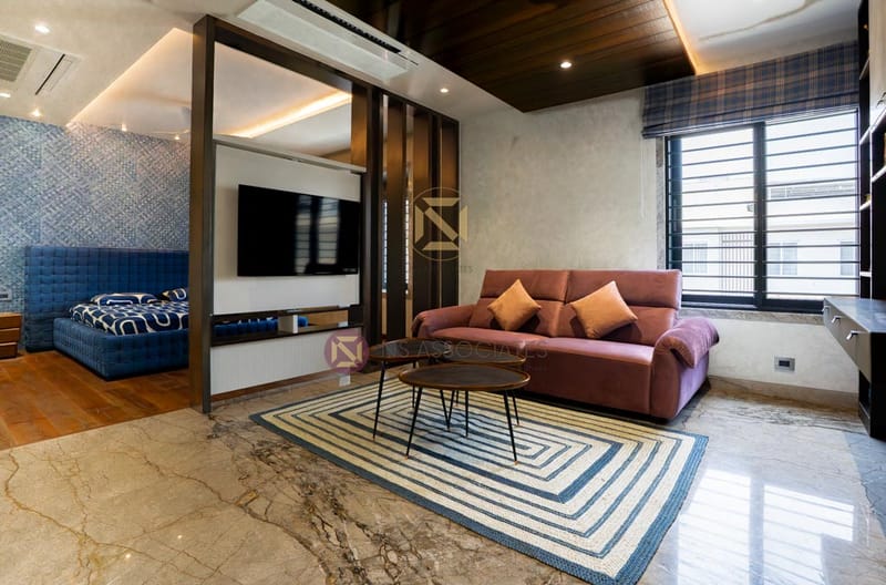 Living lounge with dusty-rose sofa, wall-mounted TV, wood-slat ceiling and marble floor with striped rug, Hyderabad
