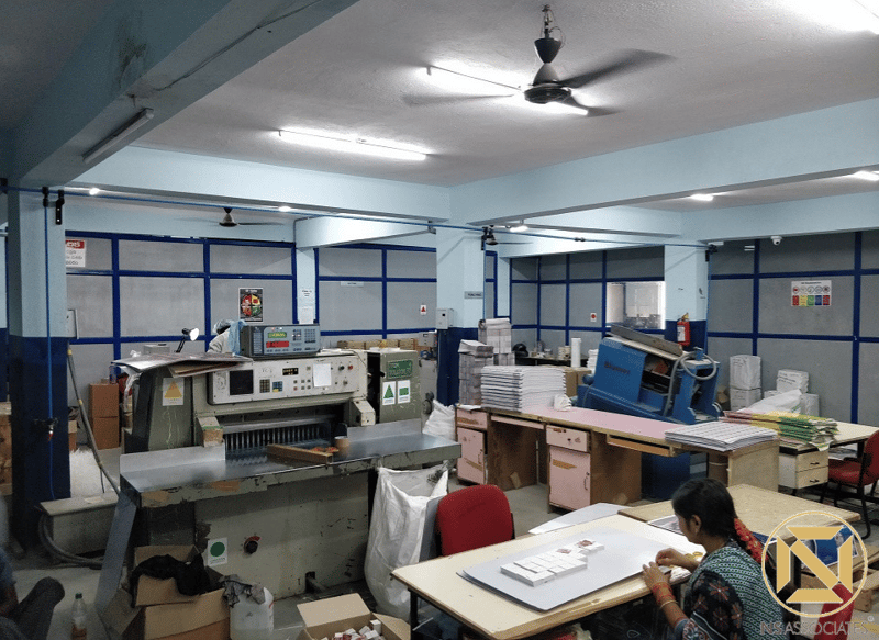 Print bindery with paper cutter, ceiling fans and blue roller-shutter bays, Hyderabad reprographics unit