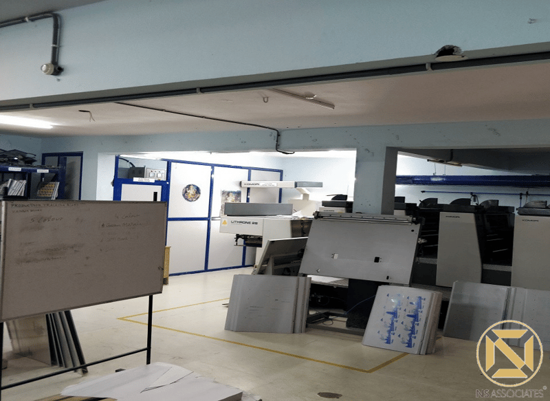 Printing production hall with finishing machinery, whiteboard and blue-trimmed partitions, Hyderabad facility
