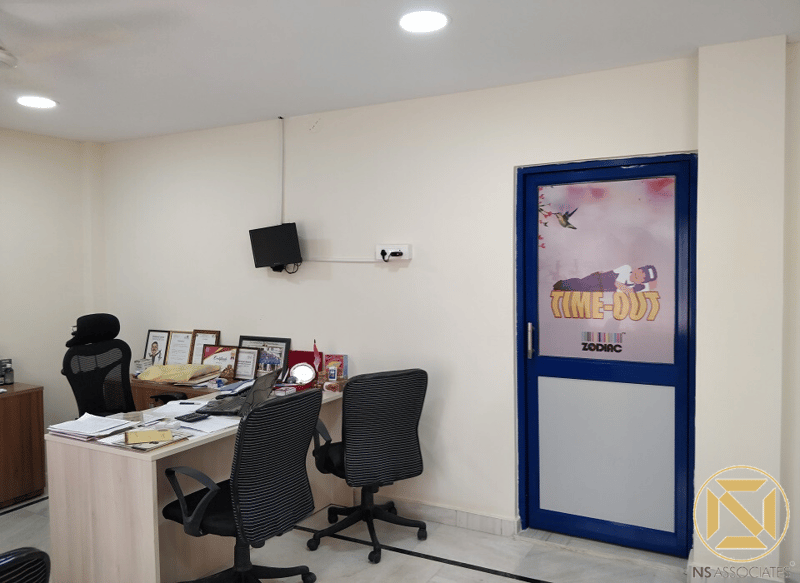 Office cabin with laminate desk, black task chairs and a bold blue framed door, Hyderabad commercial space