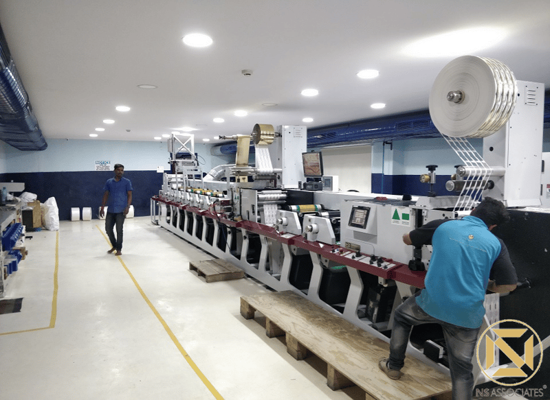 Reprographics shop floor with a long inline label press and overhead recessed lighting, Hyderabad workspace
