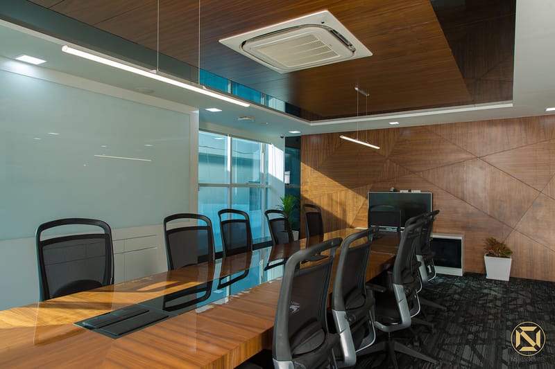 Conference room with timber table, black chairs, wall-mounted display screen and diamond-patterned wood panelling, Hyderabad office