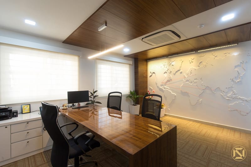 Manager's cabin with glossy wood desk, ergonomic black chairs and an etched world-map feature wall, Hyderabad