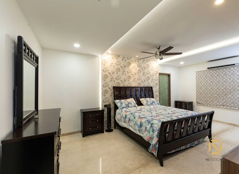Master bedroom, Hyderabad: dark-wood sleigh bed with floral bedspread, damask accent wallpaper, framed mirror and matching dresser