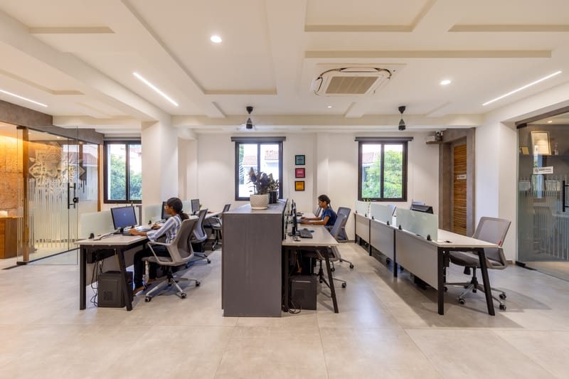 Open-plan workstation floor with staff at desks, monitors, ergonomic chairs and a coffered white ceiling in Hyderabad