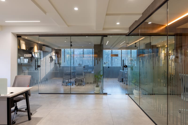 Open office with glass-walled cabins, fluted glass partitions, recessed ceiling lights and polished concrete floors in Hyderabad