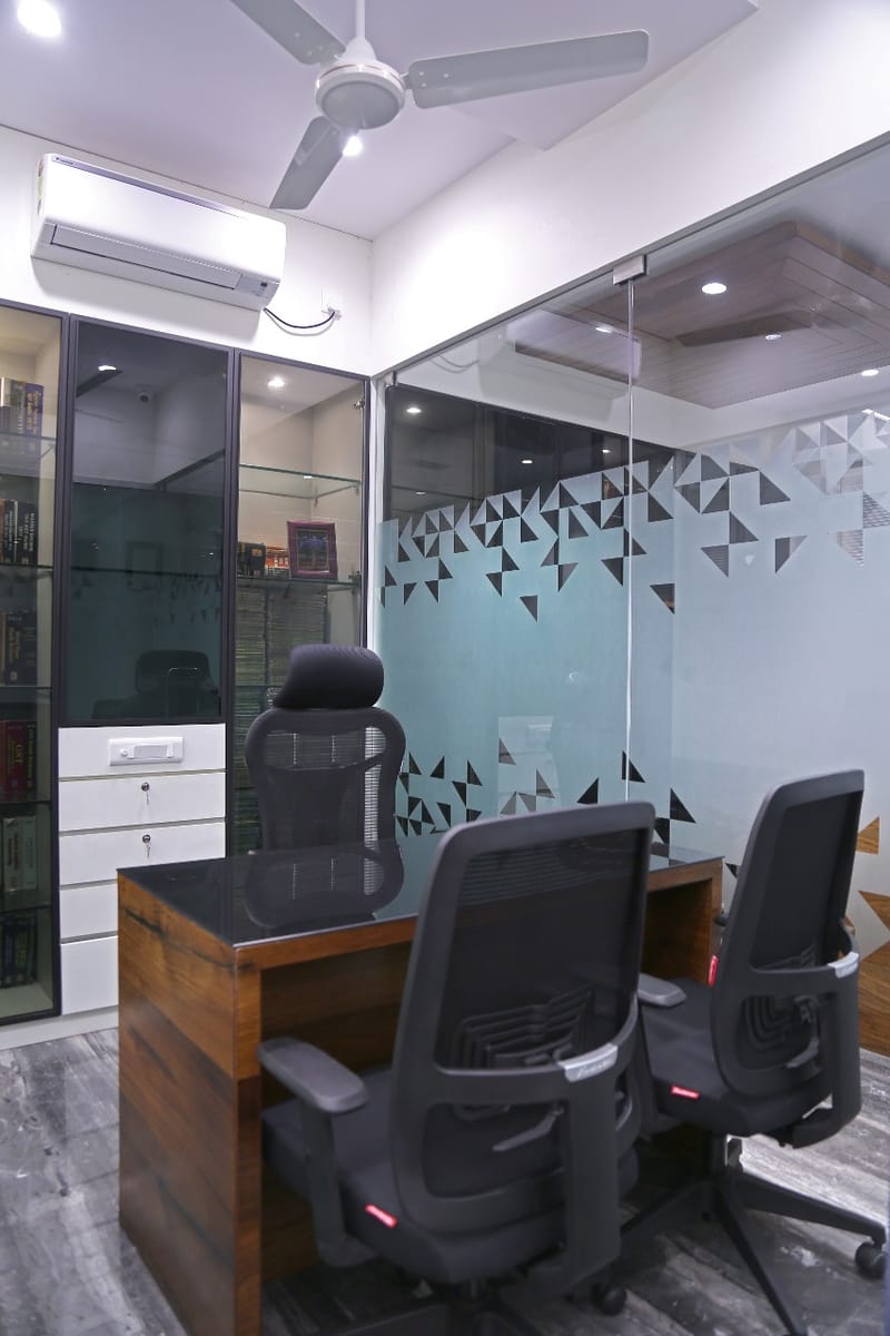 Office cabin with wood-front desk, black glass top, mesh chairs and frosted geometric glass partition, Hyderabad