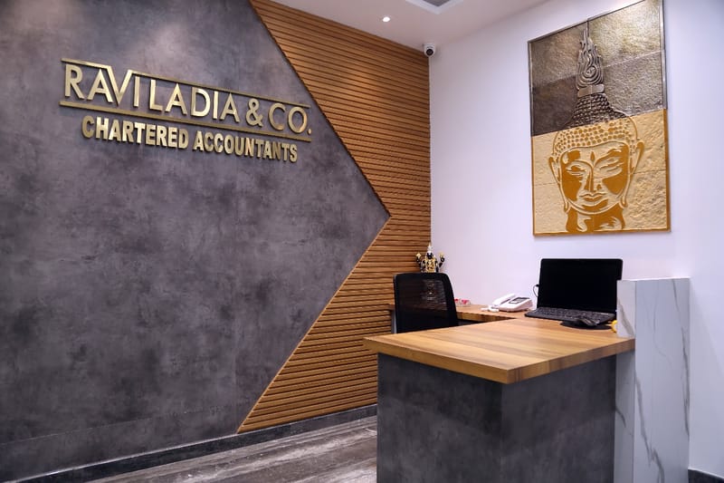 Reception desk with gold Buddha artwork, brand signage and wood-slat feature wall, Hyderabad CA office