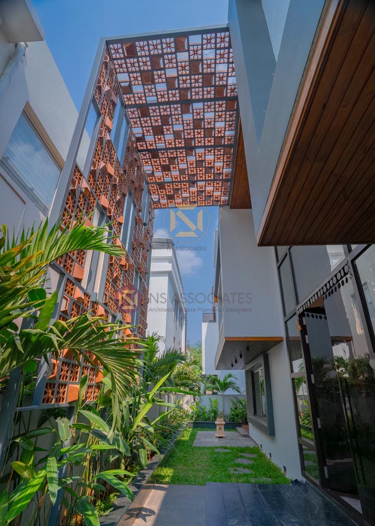 Home exterior with terracotta jali brick screen facade and landscaped courtyard with tropical plants, Hyderabad