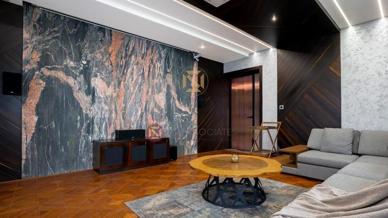 Living room with dramatic copper-veined marble TV wall, herringbone parquet floor and grey L-sofa, Hyderabad