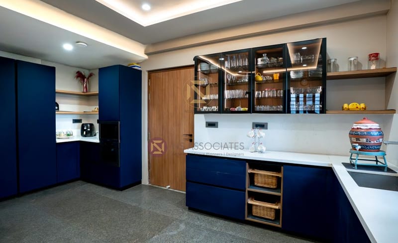 Modern kitchen with navy blue cabinets, glass-front display units and warm under-shelf lighting, Hyderabad home