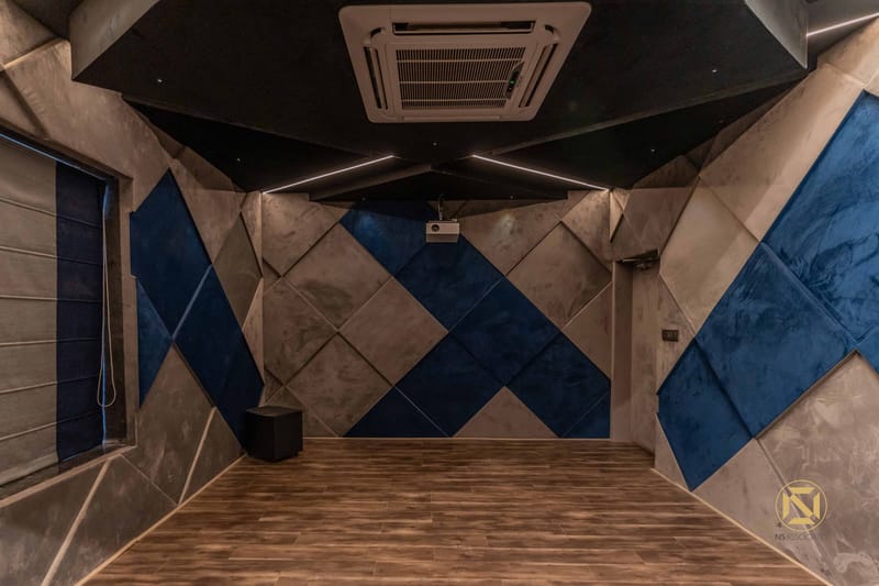 Home theatre with blue and grey diamond-pattern acoustic wall panels, wood flooring and recessed AC, Hyderabad
