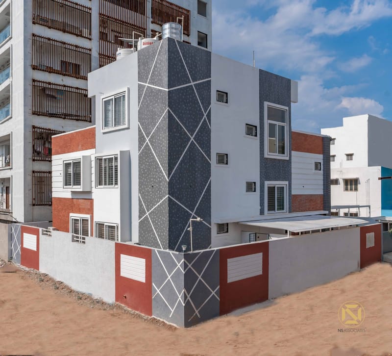 Three-storey home exterior with grey textured facade, red accent panels and white trim, Hyderabad