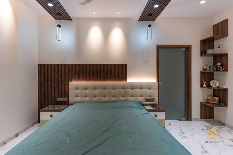 Bedroom with wood-slat headboard wall, tufted beige headboard, teal bedspread and corner display shelves, Hyderabad
