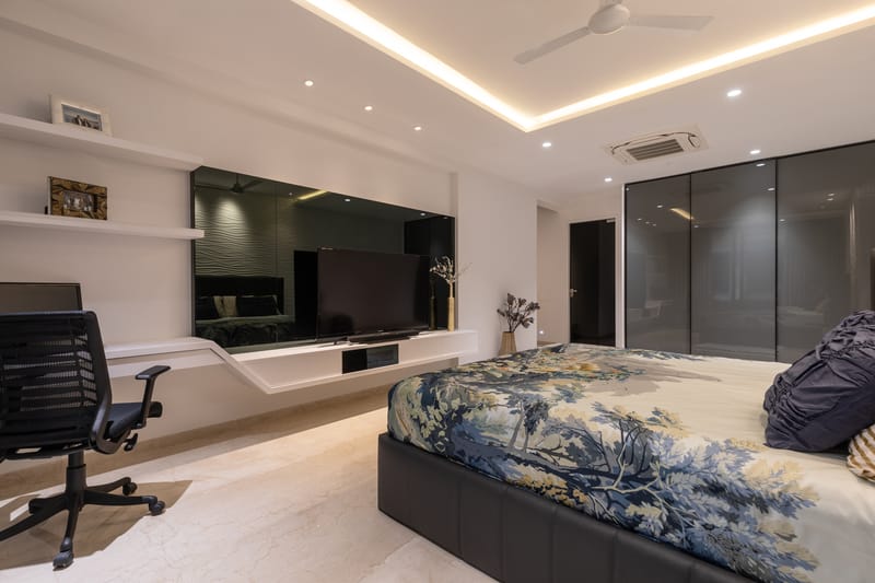 Master bedroom with mirrored TV wall, smoked-glass wardrobe, cove lighting and botanical bedspread, Hyderabad