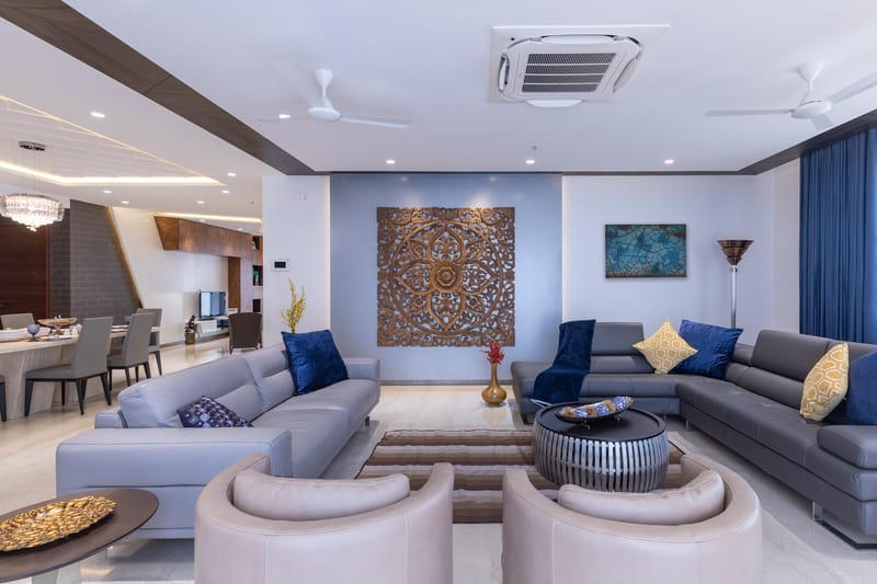 Spacious living room with two seating groups, carved wood feature panel and dining area beyond, marble floor, Hyderabad