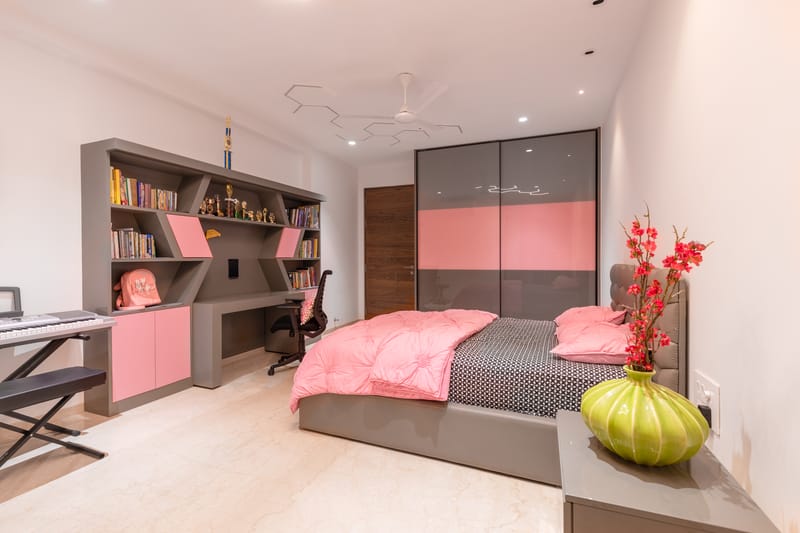 Kids' bedroom with grey-and-pink sliding wardrobe, geometric study unit, piano and bookshelf, Hyderabad