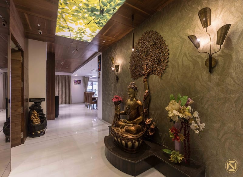 Entry foyer pooja corner with brass Buddha fountain, metal tree art, backlit ceiling and green textured wall, Hyderabad