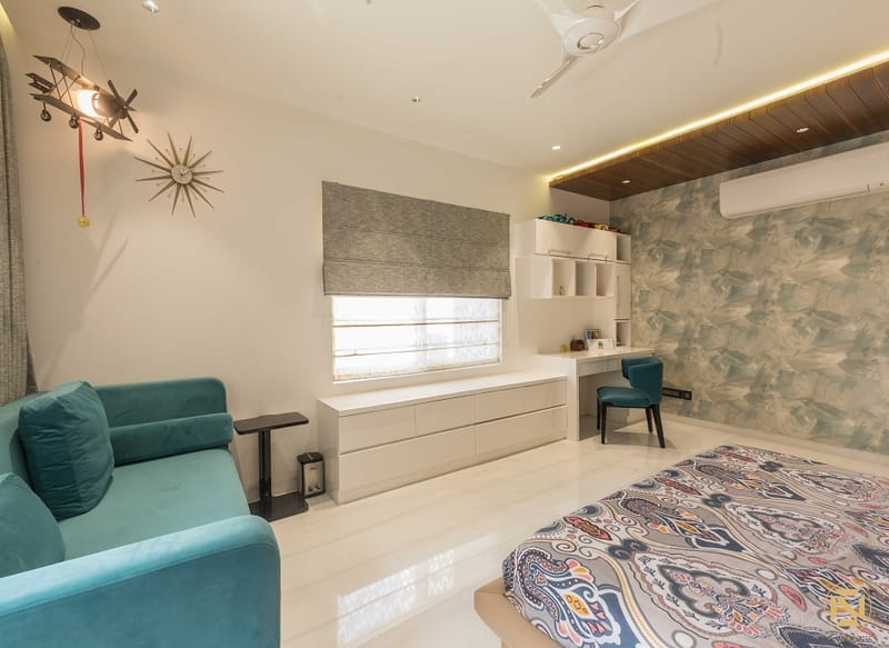 Bedroom seating area in Hyderabad with teal velvet sofa, botanical wallpaper, study desk and patterned rug
