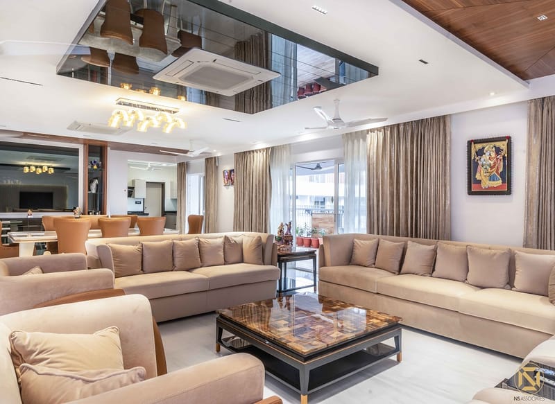 Spacious living room with twin beige sofas, marble-top coffee table, mirrored ceiling and pendant lights, Hyderabad