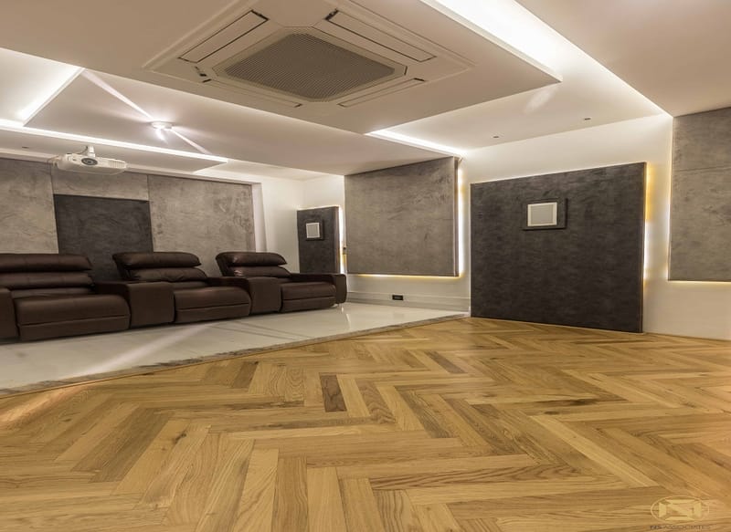 Home theatre with brown leather recliners, herringbone wood floor, grey acoustic panels and cove lighting, Hyderabad