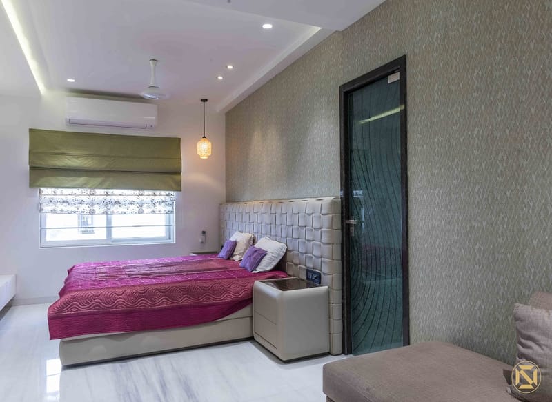 Bedroom with magenta bedspread, tufted cream headboard, textured grey wallpaper and olive roman blind, Hyderabad
