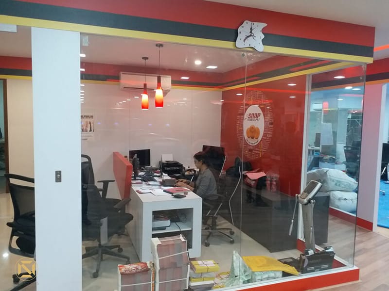 Glass-walled gym reception office with red pendant lights, desks and branded Snap Fitness signage, Hyderabad