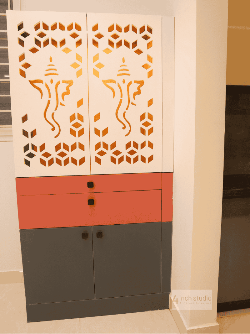 Pooja cabinet with white CNC-cut Ganesha lattice doors over coral drawers and grey base shelves, Hyderabad home