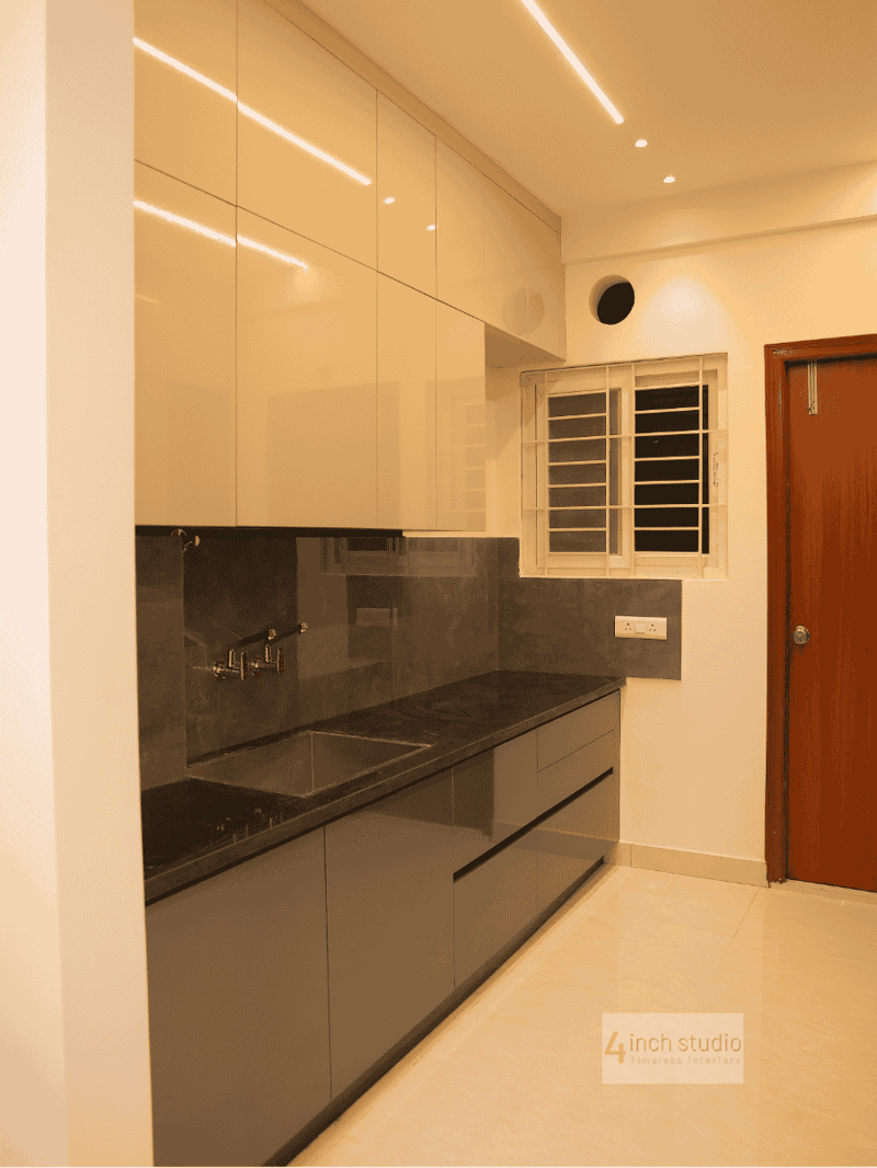 Parallel modular kitchen with glossy cream upper cabinets, grey lower units and dark granite countertop, Hyderabad apartment