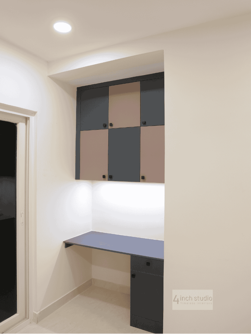 Recessed study desk in blue with grey-and-blush checkerboard cabinets and accent lighting in a Hyderabad bedroom