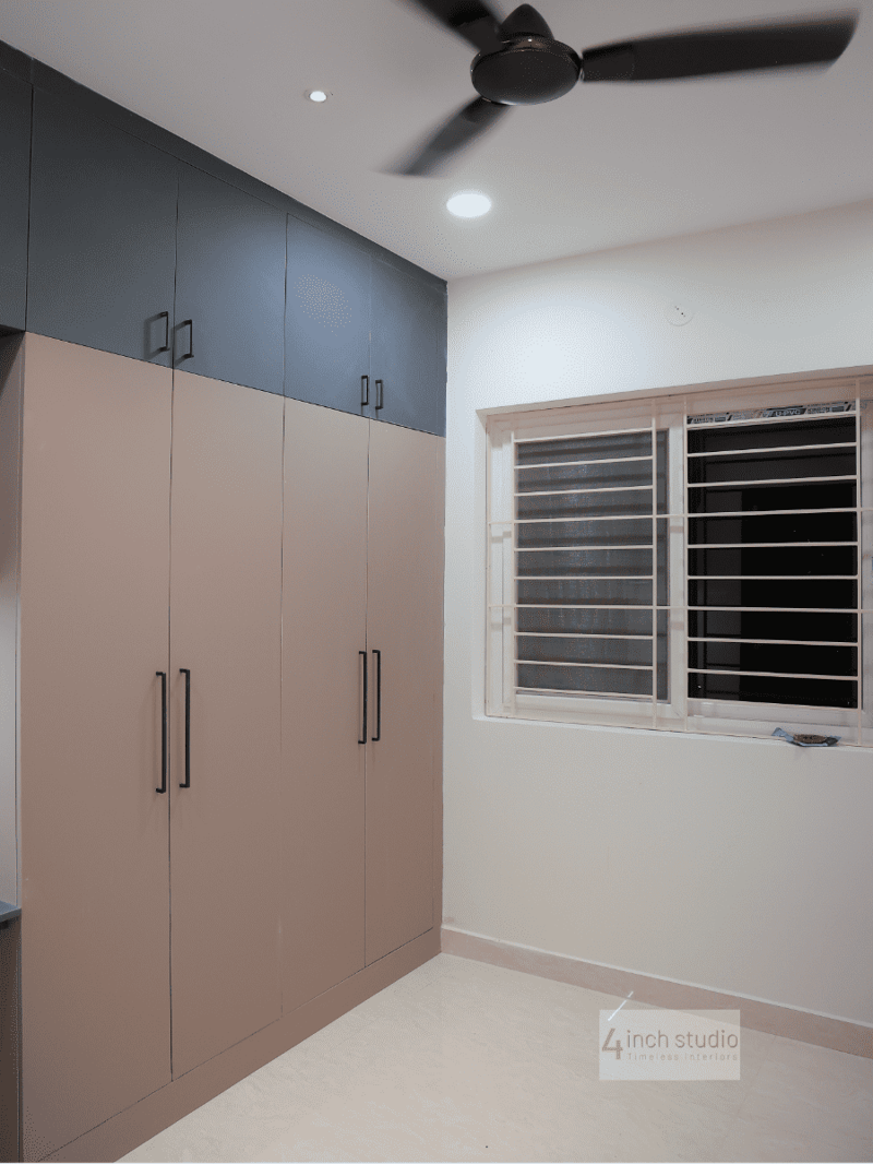 Bedroom with floor-to-ceiling wardrobe in beige laminate and navy upper shelves beside a grilled window, Hyderabad 3BHK