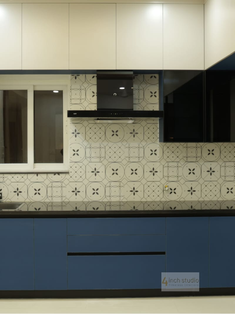 Navy and cream modular kitchen with patterned grey backsplash tiles, black granite counter and chimney, Hyderabad