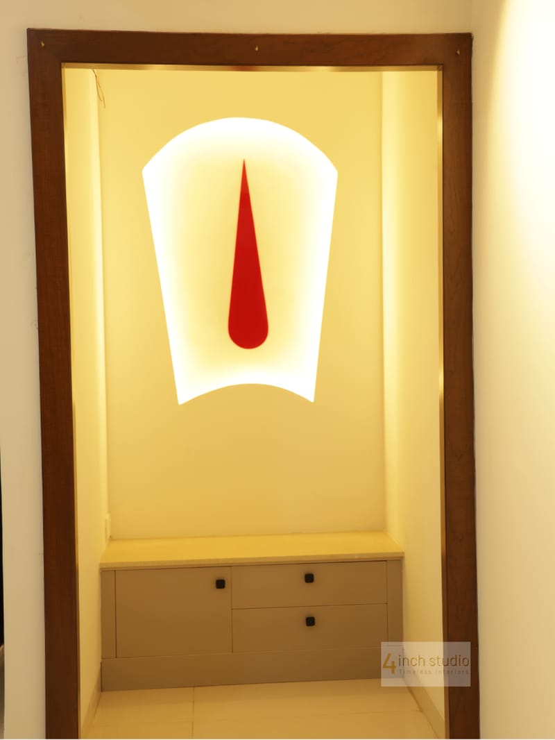 Pooja niche framed in wood with backlit panel, stylized red kalash motif and cream drawer base, Hyderabad apartment