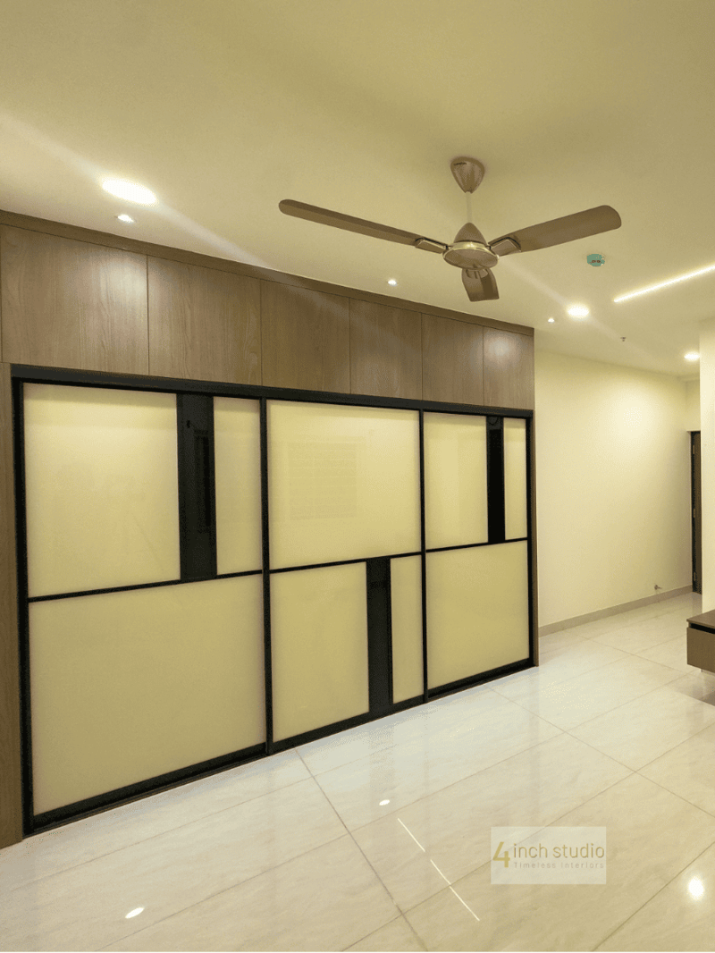 Sliding wardrobe with frosted-glass and black-framed panels under a wood loft and ceiling fan, Hyderabad
