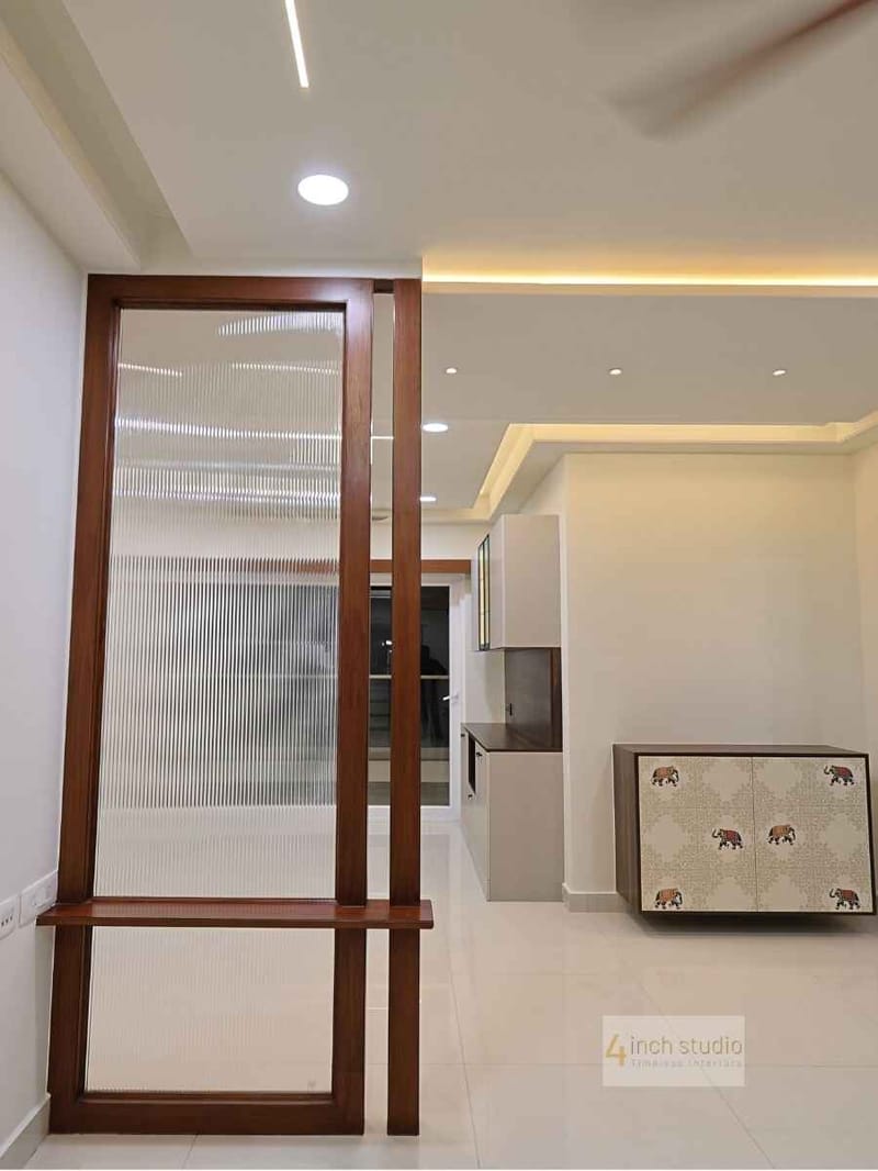 Foyer with a fluted-glass teak partition and bench leading to a kitchen, with elephant-print cabinet, Hyderabad