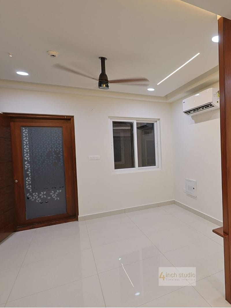 Empty bedroom with laser-cut jali wood door panel, split AC and linear-lit false ceiling, Hyderabad apartment