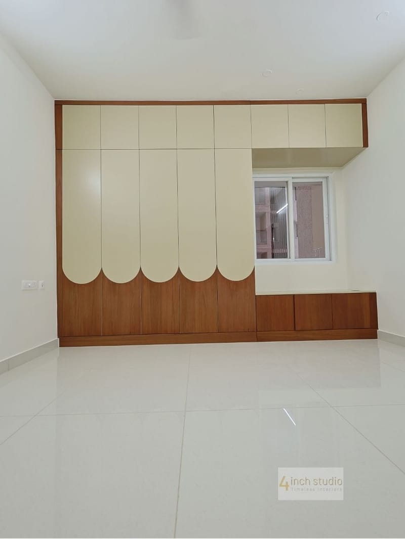 Bedroom wardrobe with scalloped cream and woodgrain shutters beside a window and low storage cabinet, Hyderabad