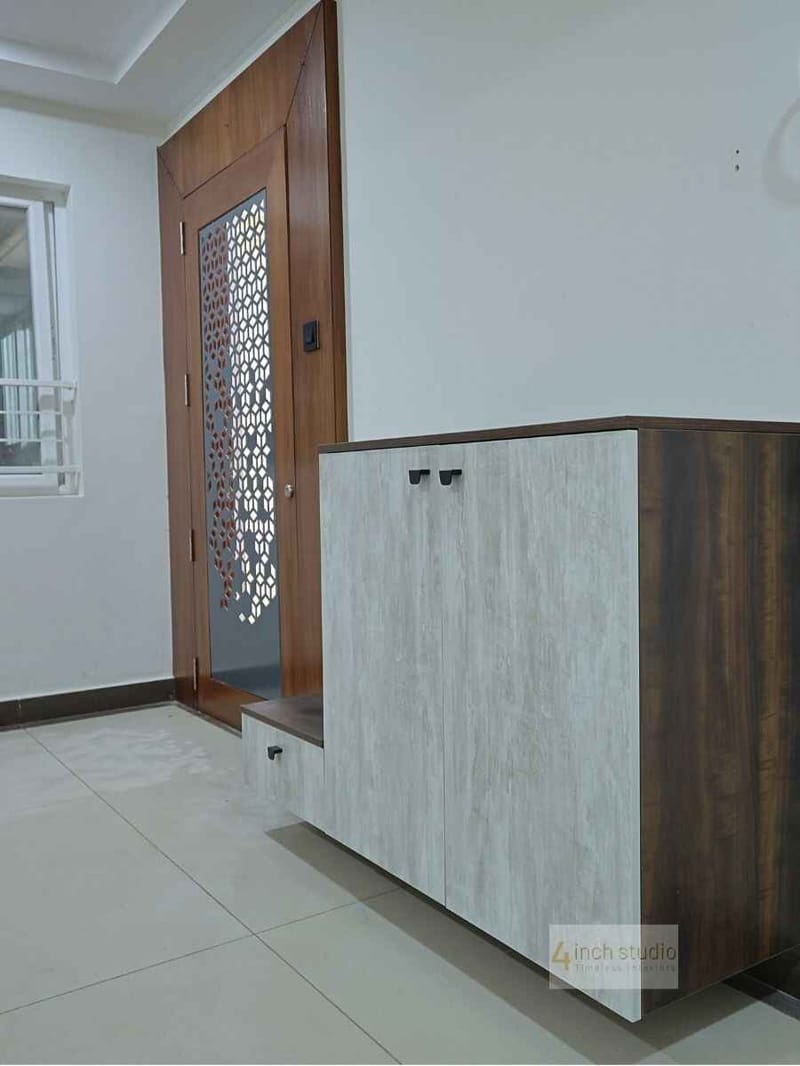 Foyer with light travertine-finish shoe cabinet and teak jali entry door over tiled flooring, Hyderabad
