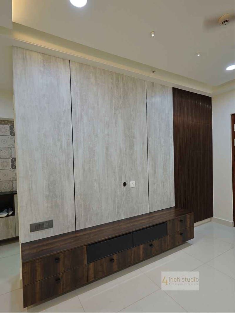 Living room TV wall in travertine-look laminate with a fluted dark-wood panel and walnut console, Hyderabad