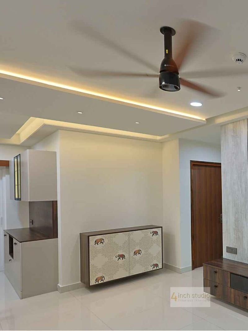 Hyderabad living room with layered false ceiling, recessed lights and a printed elephant-motif storage cabinet