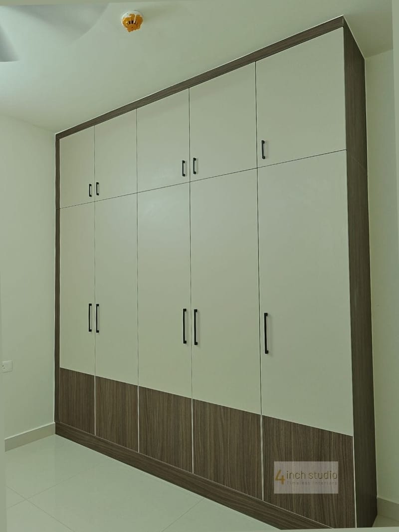 Five-door bedroom wardrobe in cream laminate with woodgrain trim and base band, Hyderabad apartment