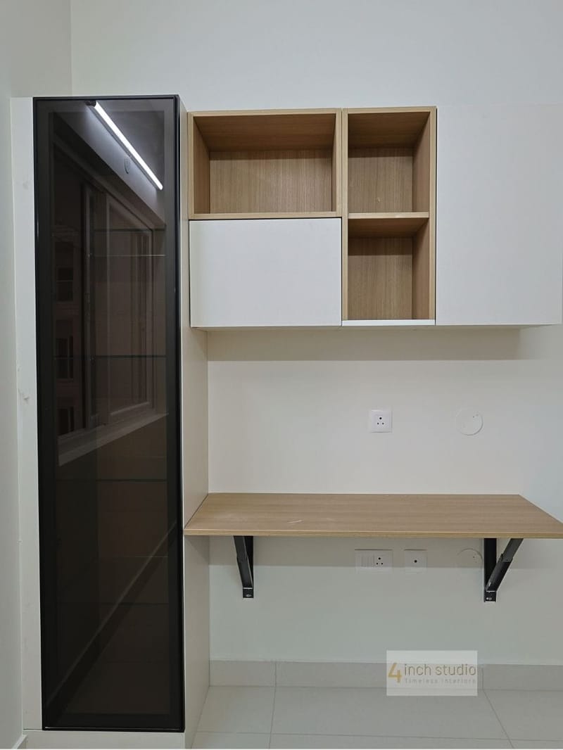 Study nook with wall-mounted wood desk, open shelves with sliding box and tall tinted-glass cabinet, Hyderabad apartment