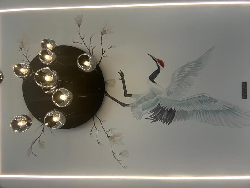 Hand-painted crane and magnolia ceiling mural framed by a black disc chandelier of chrome globe pendants and LED cove light