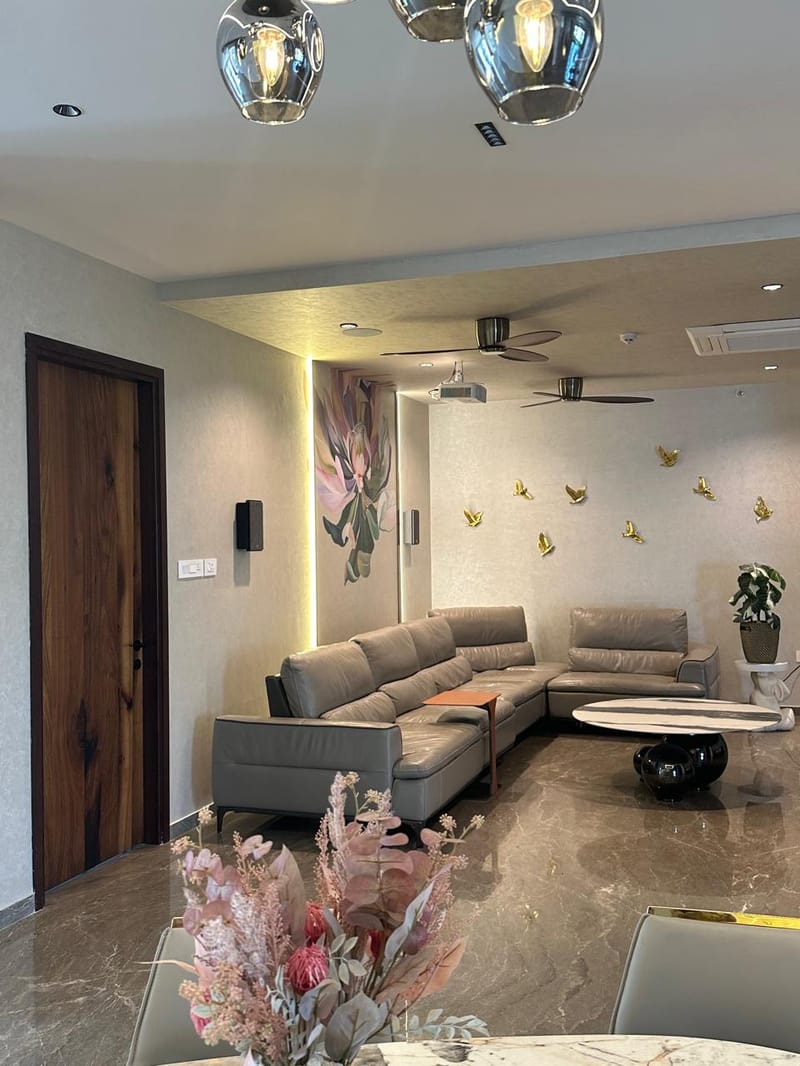 Open living-dining room with grey leather sectional, magnolia wall mural, brass flying-bird decor and marble flooring, Hyderabad